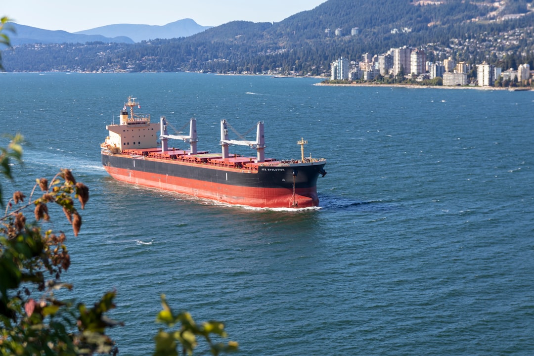 cargo-ship-sailing-near-city-bmpjcuc9dv8
