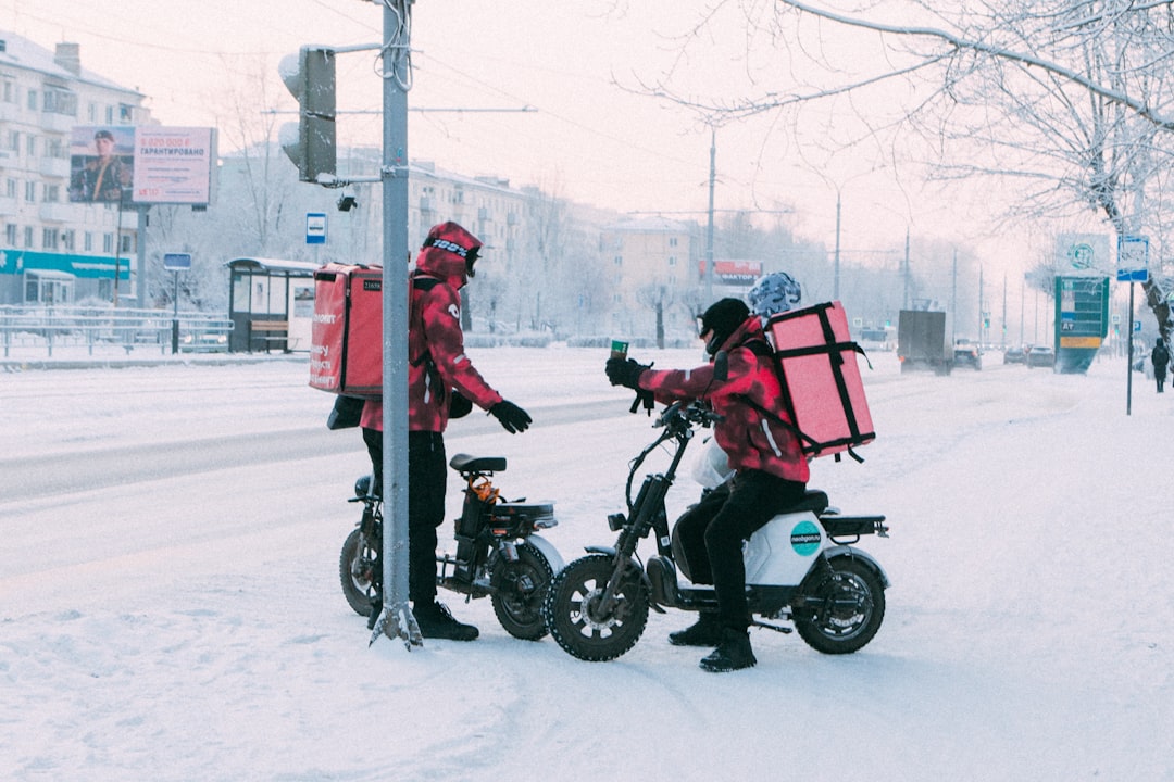 delivery-workers-on-scooters-in-snowy-city-street-83lyh3ckkji